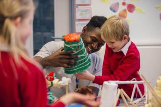 A male teacher helping young male student with science-based, arts and crafts